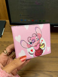 Pink cartoon character on a pink wallet held by a hand with a blurred background
