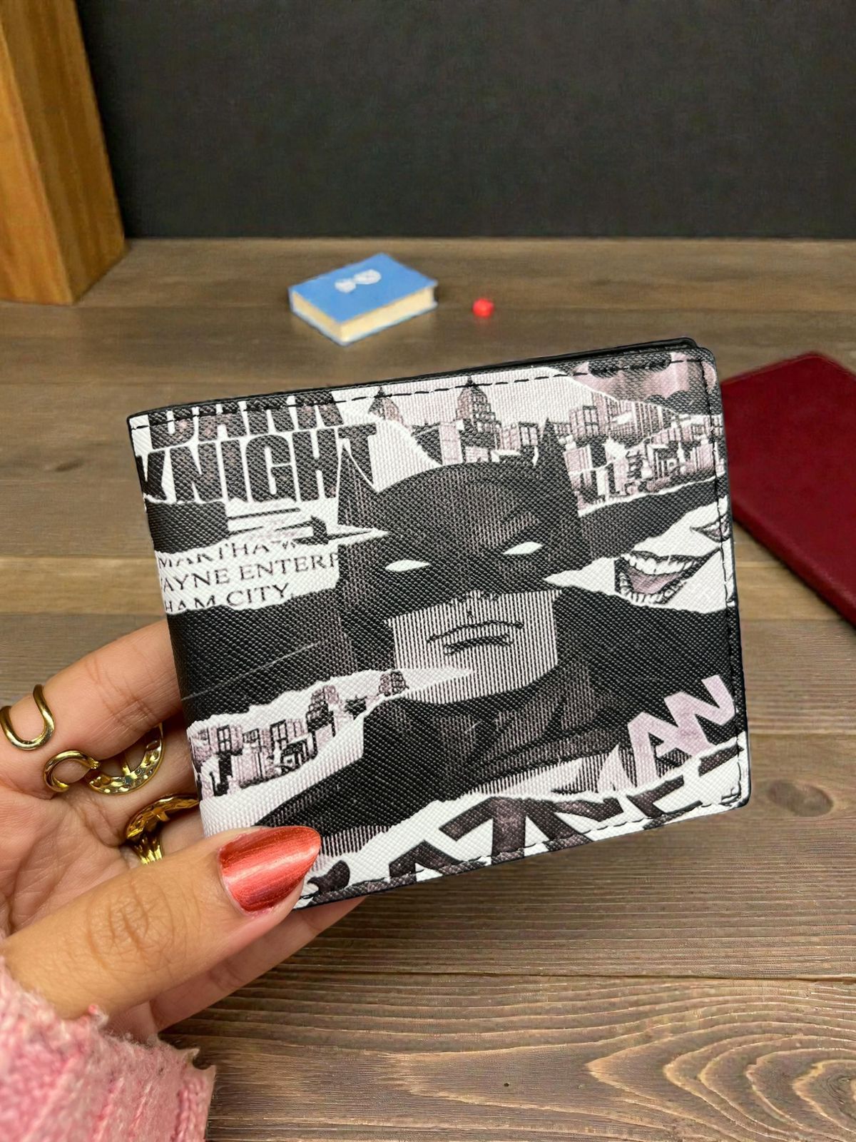 Batman-themed wallet held by a hand on a wooden surface